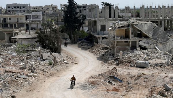 A man rides a motorbike past damaged buildings in the rebel-held town of Nairab, Idlib region, Syria April 17, 2020. Picture taken April 17, 2020. - Sputnik International