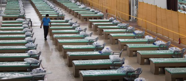 A worker walks amidst beds made out of cardboard inside the campus hall of spiritual organisation Radha Soami Satsang Beas (RSSB), converted into a COVID-19 coronavirus care centre, in New Delhi on July 6, 2020 - Sputnik International