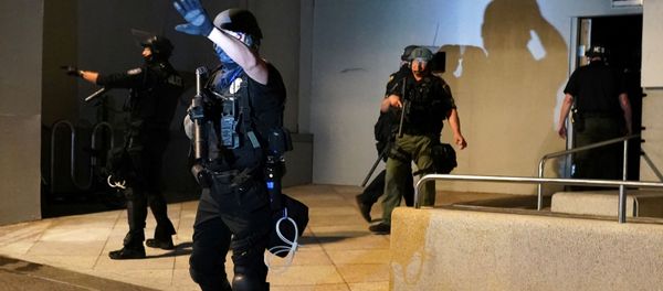 A Portland Police Bureau officer shields his eyes from a flashlight after confronting a crowd during a protest against racial inequality in Portland, Oregon, US July 17, 2020 - Sputnik International