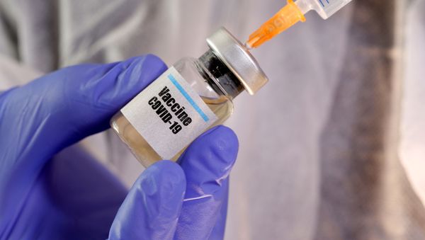 A woman holds a small bottle labeled with a Vaccine COVID-19 sticker and a medical syringe in this illustration taken April 10, 2020. - Sputnik International