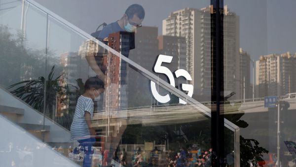 A man and a child wearing face masks following the coronavirus disease (COVID-19) outbreak walk past a 5G sign inside a Huawei store at a shopping mall in Beijing, China July 14, 2020 - Sputnik International