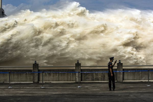 This photo taken on July 19, 2020, shows a security guard looking at his smartphone while water is released from the Three Gorges Dam, a gigantic hydropower project on the Yangtze river, to relieve flood pressure in Yichang, central China's Hubei province This photo taken on July 19, 2020, shows a security guard looking at his smartphone while water is released from the Three Gorges Dam, a gigantic hydropower project on the Yangtze river, to relieve flood pressure in Yichang, central China's Hubei province - Sputnik International