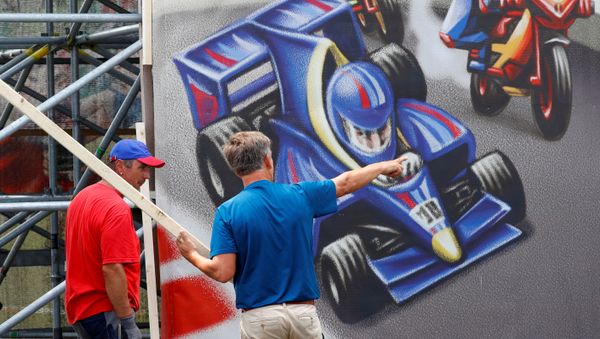 Workers stand in front of a poster next to the Formula One race track in Spielberg, Austria July 1, 2020 - Sputnik International