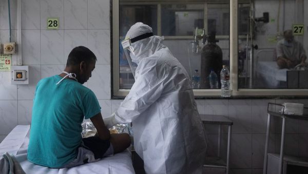 Medical workers wearing personal protective equipment (PPE) tend to a patient suffering from the coronavirus disease  - Sputnik International