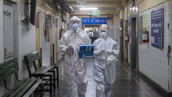 Medical workers wearing personal protective equipment (PPE) walk through a ward for patients suffering from the coronavirus disease  - Sputnik International