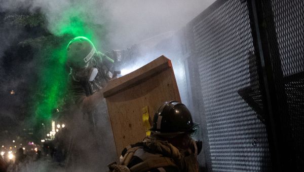 A protester standing on barriers near the fence is shot with pepper balls by federal law enforcement officers during a demonstration against police violence and racial inequality in Portland, Oregon, U.S., July 29, 2020.  - Sputnik International