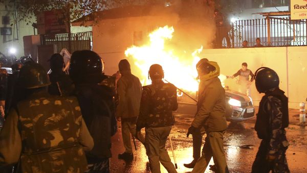 A man tries to put out fire from a burning car during demonstrations against India's new citizenship law in New Delhi on December 20, 2019 - Sputnik International