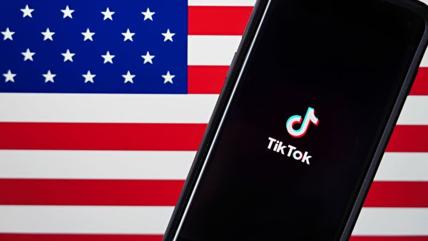 In this photo illustration, a mobile phone featuring the TikTok app is displayed next to the American flag on August 03, 2020 in New York City. Under threat of a U.S. ban on the popular social media app, it has been reported that Microsoft is considering taking over from Chinese firm ByteDance. - Sputnik International