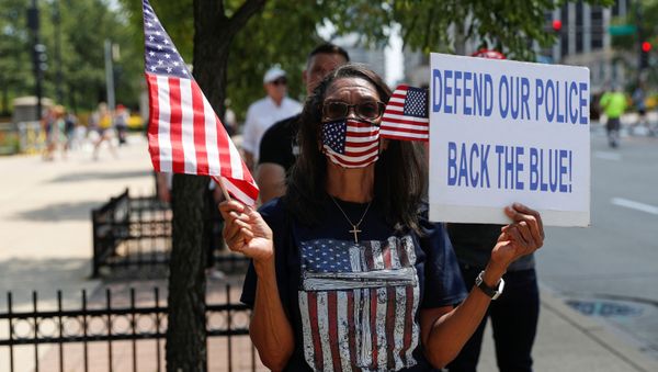 A woman holds a flag and placard as she attends a Back the Blue rally in support and solidarity with law enforcement, in Chicago, Illinois, U.S., July 25, 2020. A woman holds a flag and placard as she attends a Back the Blue rally in support and solidarity with law enforcement, in Chicago, Illinois, U.S., July 25, 2020. - Sputnik International