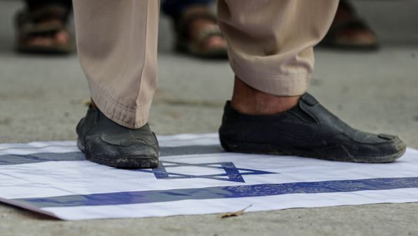 A supporter of religious and political party Jamaat-e-Islami (JI) steps on an Israeli flag to condemn the diplomatic agreement between the United Arab Emirates (UAE) and Israel, during a protest in Karachi, Pakistan August 16, 2020. - Sputnik International