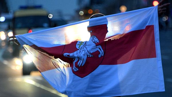 A Belarus opposition supporter holds a flag during a rally on the Independence Square, in Minsk, Belarus A Belarus opposition supporter holds a flag during a rally on the Independence Square, in Minsk, Belarus - Sputnik International
