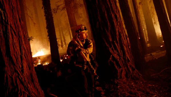 Cal Fire firefighter Anthony Quiroz carries a hose as he defends a home during the CZU Lightning Complex Fire in Boulder Creek, California, 21 August 2020. - Sputnik International