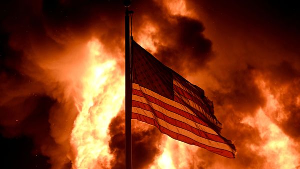 Flames engulf the Community Corrections Division building as an American flag flutters on a pole in an arson attack after a black man identified as Jacob Blake, was shot several times by police in Kenosha, Wisconsin, 24 August 2020.  - Sputnik International