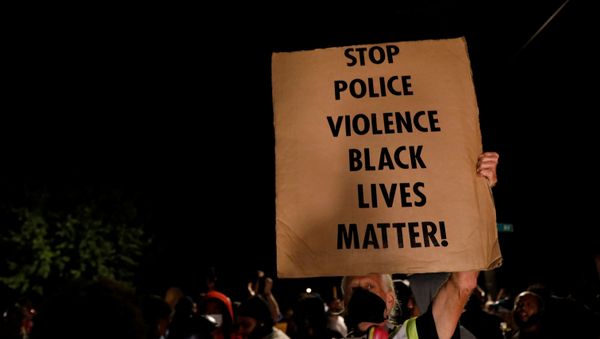 A man holds up a sign as demonstrators take part in a protest following the police shooting of Jacob Blake, a Black man, in Kenosha, Wisconsin, U.S. August 26, 2020.  - Sputnik International