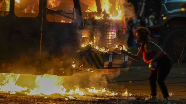 A protester lights a cigarette on a garbage truck that was set on fire during protests late Monday, Aug. 24, 2020, in Kenosha, Wis., sparked by the shooting of Jacob Blake by a Kenosha Police officer a day earlier.  - Sputnik International