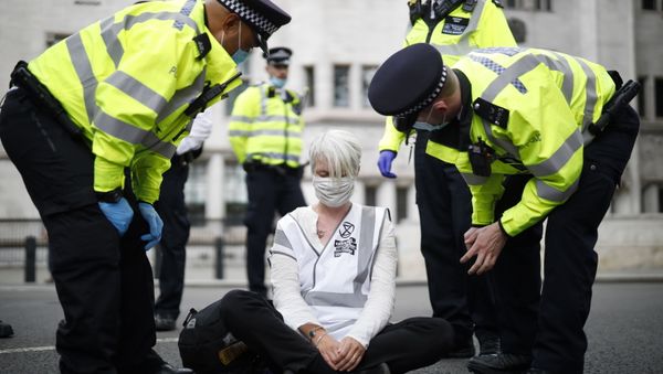 Police officers talk to an activist from the climate protest group Extinction Rebellion who is sat in the road in Parliament Square in central London on September 2, 2020 on the second day of the group's new series of 'mass rebellions'. - Sputnik International