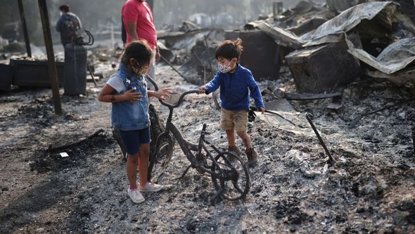 Ashley, 3, and Ethan, 2, look at a burned bicycle after wildfires destroyed a neighbourhood in Bear Creek, Phoenix, Oregon, U.S., September 10, 2020. - Sputnik International