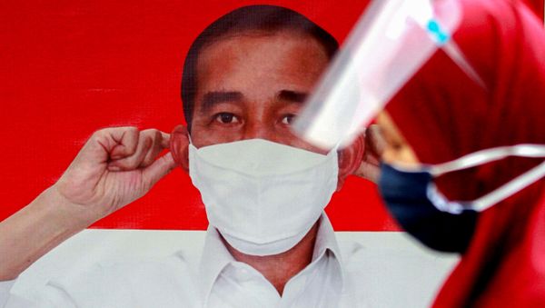 A woman wearing a protective face mask and a face shield walks past a banner depicting Indonesian President Joko Widodo promoting awareness of the coronavirus disease (COVID-19) at Tanah Abang Station, in Jakarta, Indonesia, September 14, 2020. - Sputnik International