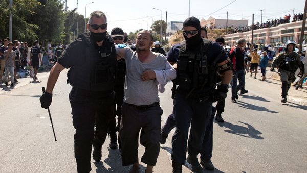 A man is detained by police officers as refugees and migrants from the destroyed camp of Moria clash with the police, on the island of Lesbos, Greece, September 12, 2020. - Sputnik International