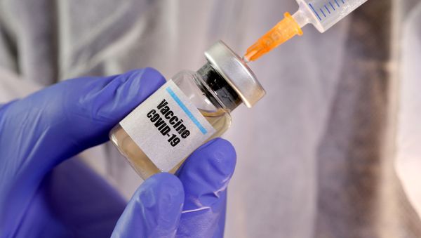 A woman holds a small bottle labeled with a Vaccine COVID-19 sticker and a medical syringe in this illustration - Sputnik International