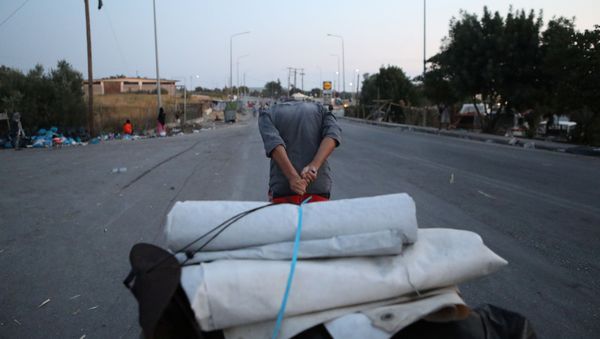 A man drags his belongings as refugees and migrants from the destroyed Moria camp walk towards a new temporary camp, on the island of Lesbos, Greece, September 18, 2020 - Sputnik International