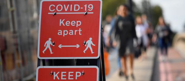 Pedestrians walk near public health signs, whilst the reproduction R number of COVID-19 infections in the United Kingdom has risen and may be above 1, the Government Office for Science said on Friday, indicating a risk that the overall epidemic is growing, London, Britain, September 11, 2020 - Sputnik International