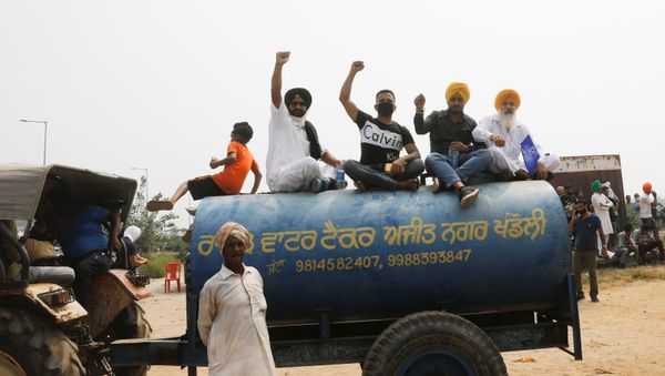 Farmers sit on the water tank as they block a national highway during a protest against farm bills passed by India's parliament Farmers sit on the water tank as they block a national highway during a protest against farm bills passed by India's parliament - Sputnik International