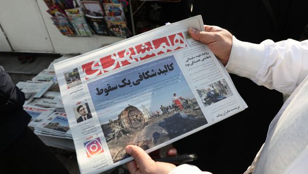 An Iranian holds a newspaper with a picture of the debris of the Ukrainian plane that crashed in Tehran earlier this week, outside a news stand in the Islamic republic's capital on January 11, 2020. - Sputnik International