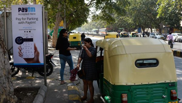 In this photograph taken on February 27, 2017, Indian pedestrians walk past a sign advertising Indian electronic and cellphone-based payment system Paytm outside a parking area in New Delhi - Sputnik International
