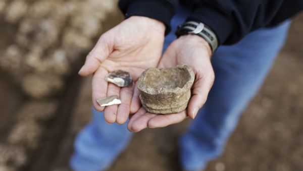  Yoav Arbel of Israel's Antiquities Authority holds pieces of stone artifacts at the excavation site of the Neolithic period in Tel Aviv, Israel, Jan. 11, 2010. Israel's Antiquities Authority say the remains of a prehistoric building as well as ancient flint tools have been discovered in the modern city of Tel Aviv - Sputnik International