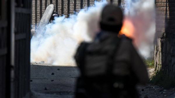 A security personnel (R) fires tear gas towards protesters during clashes with government forces in Batamaloo area of Srinagar on September 17, 2020.  - Sputnik International