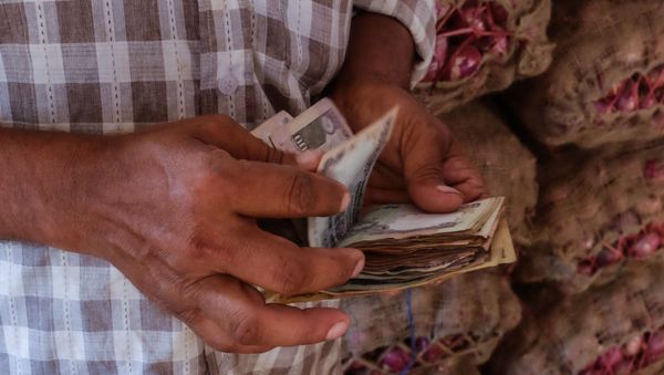 An Indian man counts his money as he pays for a 60 kilo sack of onions at a local market in south New Delhi on September 9, 2015. - Sputnik International