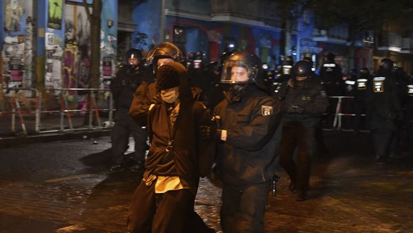 Police officers are taking away a demonstrator in Rigaer Street who protests against the eviction of the occupied house Liebig 34 in Berlin, Germany, Friday, Oct. 9, 2020. Police in heavy riot gear began clearing out a notorious Berlin leftist squat on Friday morning, encountering only passive resistance from residents as they carried them individually down a firetruck's ladder. Police spokesman at the scene Thilo Cablitz said some 1,500 police had been called out to aid in clearing the so-called Liebig 34 squat in the capital's Friedrichshain neighborhood, named after its address Liebigstrasse 34. (Paul Zinken/dpa via AP) - Sputnik International