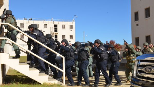 Multiple departments practice serving a notional warrant in an apartment sized complex Nov. 8. At Fort Bragg, N.C., The Fort Bragg Special Reaction Team hosts North Carolina sheriffs and police departments special reaction and tactical training exercise. The teams practice rappelling from a multi-story structure, respond to a notional officer down call, operate in a smoky or chemical environment performing search and rescue, and serve a search warrant at an apartment complex in a joint-team scenario. The military operations on urban terrain range here, provides similar structures to those encountered by law enforcement officers. This is the second year the North Carolina Tactical Officer Association has held SRT training at Fort Bragg. Multiple departments practice serving a notional warrant in an apartment sized complex Nov. 8. At Fort Bragg, N.C., The Fort Bragg Special Reaction Team hosts North Carolina sheriffs and police departments special reaction and tactical training exercise. The teams practice rappelling from a multi-story structure, respond to a notional officer down call, operate in a smoky or chemical environment performing search and rescue, and serve a search warrant at an apartment complex in a joint-team scenario. The military operations on urban terrain range here, provides similar structures to those encountered by law enforcement officers. This is the second year the North Carolina Tactical Officer Association has held SRT training at Fort Bragg. - Sputnik International