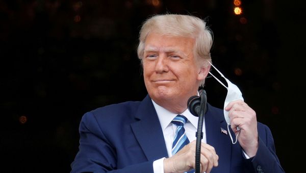 U.S. President Donald Trump takes off his face mask as he comes out on a White House balcony to speak to supporters gathered on the South Lawn for a campaign rally that the White House is calling a peaceful protest in Washington, U.S., October 10, 2020 - Sputnik International