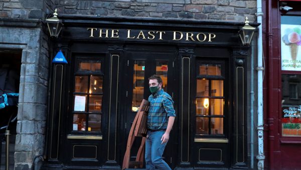 A worker carries a chair as he prepares to close a pub at Grassmarket, amid the coronavirus disease (COVID-19) outbreak, in Edinburgh, Britain October 9, 2020.  - Sputnik International