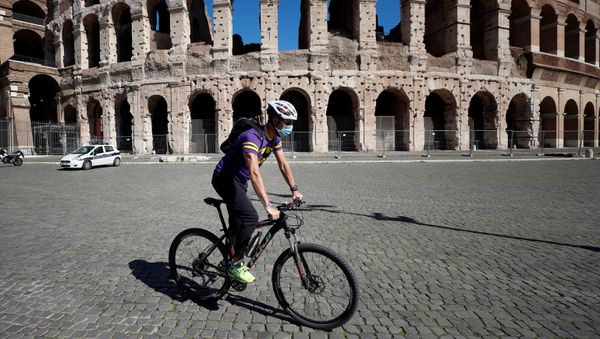 A man wearing a protective face mask cycles past the Colosseum as local authorities in the Italian capital Rome ordered face coverings to be worn at all times outdoors, in an effort to counter the spread of the coronavirus disease (COVID-19), in Rome, Italy, October 8, 2020. - Sputnik International