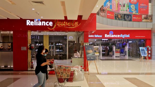 A customer wearing a protective mask pushes a trolley with grocery items past Reliance Jewels and Reliance Digital stores in Mumbai, India. - Sputnik International