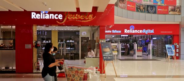 A customer wearing a protective mask pushes a trolley with grocery items past Reliance Jewels and Reliance Digital stores in Mumbai, India. - Sputnik International