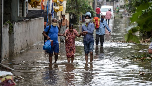 Residents carrying their belongings help a woman (C) while making their way on a flooded street following heavy rains in Hyderabad on October 14, 2020.  - Sputnik International