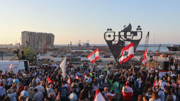 Lebanese protesters gather to light the October 17 torch marking the one year anniversary of the beginning of a nationwide anti-government protest movement, in front of the devastated port of the capital Beirut where a massive explosion took place more than two months ago, on October 17, 2020. - Hundreds marched in Lebanon's capital to mark the first anniversary of a non-sectarian protest movement that has rocked the political elite but has yet to achieve its goal of sweeping reform. - Sputnik International