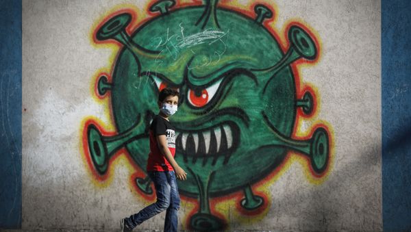 A Palestinian boy walks past street art showing a malevolent coronavirus, in Gaza city on 22 September 2020. - Sputnik International