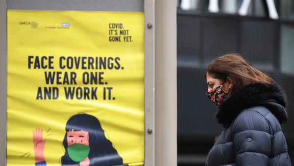 A woman wearing a facemask walks past a poster urging people to wear face coverings, in Manchester, north west England on October 13, 2020, as the number of cases of the novel coronavirus COVID-19 continue to rise. A woman wearing a facemask walks past a poster urging people to wear face coverings, in Manchester, north west England on October 13, 2020, as the number of cases of the novel coronavirus COVID-19 continue to rise. - Sputnik International