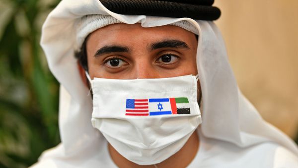 A picture taken on August 31, 2020, shows an Emirati man, wearing a protective mask with the flags of the US, Israel and the UAE, ahead of the arrival of the first commercial flight from Israel, carrying a US-Israeli delegation to the UAE following a normalisation accord, at the Abu Dhabi airport - Sputnik International