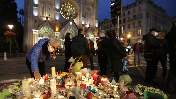 A woman lights a candle outside Notre-Dame de l'Assomption Basilica in Nice on October 31, 2020, to pay tribute to the victims two days after a knife attacker killed three people, cutting the throat of two, inside the church of the French Riviera city, and police arrest a young Tunisian migrant from Sfax who arrived in Europe only last month, according to French prosecutors. (Photo by Valery HACHE / AFP) A woman lights a candle outside Notre-Dame de l'Assomption Basilica in Nice on October 31, 2020, to pay tribute to the victims two days after a knife attacker killed three people, cutting the throat of two, inside the church of the French Riviera city, and police arrest a young Tunisian migrant from Sfax who arrived in Europe only last month, according to French prosecutors. (Photo by Valery HACHE / AFP) - Sputnik International