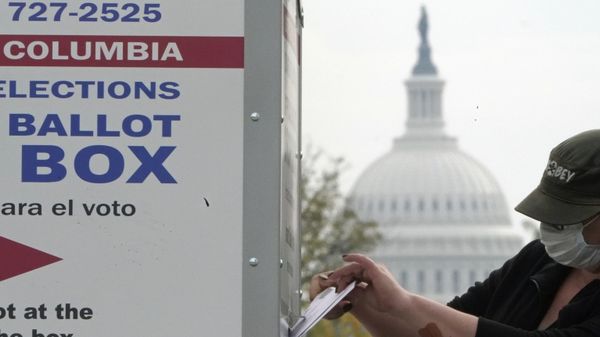 With the U.S. Capitol dome visible, a voter drops a ballot into an early voting drop box, Wednesday, 28 October 2020, at Union Market in Washington. - Sputnik International