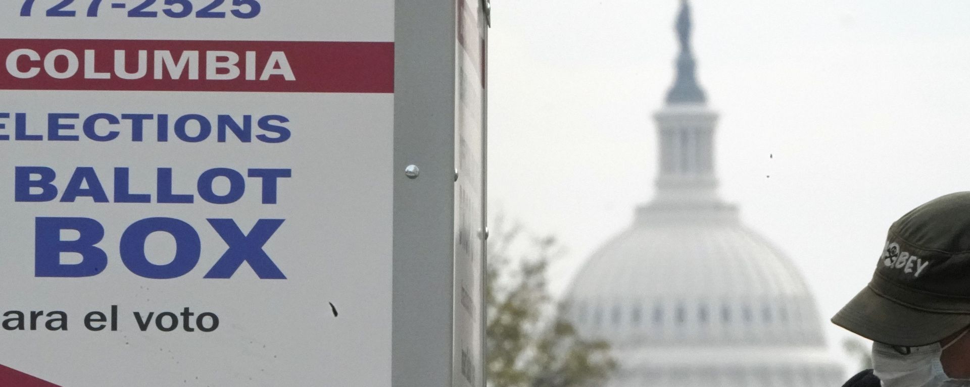 With the US Capitol dome visible, a voter drops a ballot into an early voting drop box, Wednesday, Oct. 28, 2020, at Union Market in Washington.
 - Sputnik International, 1920, 26.02.2023