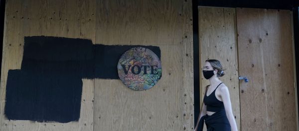 A woman walks past a Vote sign on wooden boards covering the exterior of Chloe Gallery in San Francisco, Monday, Nov. 2, 2020, ahead of Election Day.  - Sputnik International