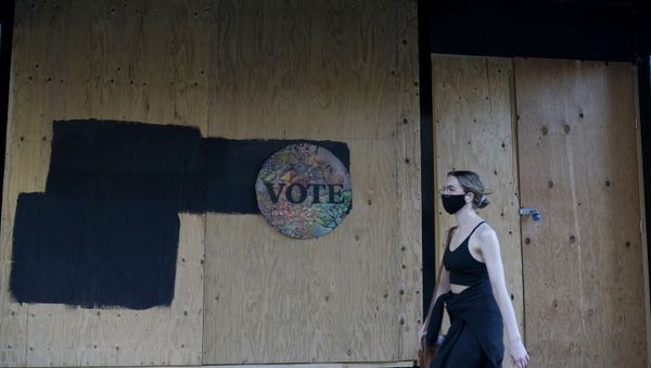 A woman walks past a Vote sign on wooden boards covering the exterior of Chloe Gallery in San Francisco, Monday, Nov. 2, 2020, ahead of Election Day.  - Sputnik International