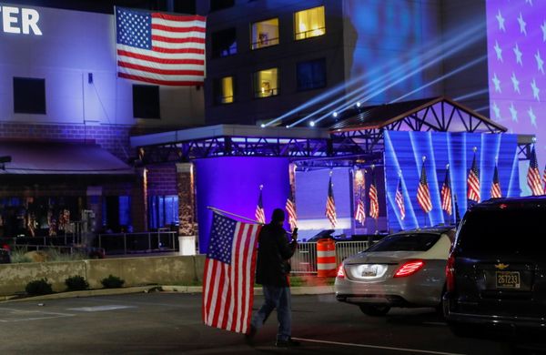 A Biden supporter carries an American flag across the parking lot where US presidential nominee for the Democrats, Joe Biden, will hold his 2020 US presidential election night event as a drive-in rally because of coronavirus restrictions, in Wilmington, Delaware, US, 3 November 2020. A Biden supporter carries an American flag across the parking lot where US presidential nominee for the Democrats, Joe Biden, will hold his 2020 US presidential election night event as a drive-in rally because of coronavirus restrictions, in Wilmington, Delaware, US, 3 November 2020. - Sputnik International